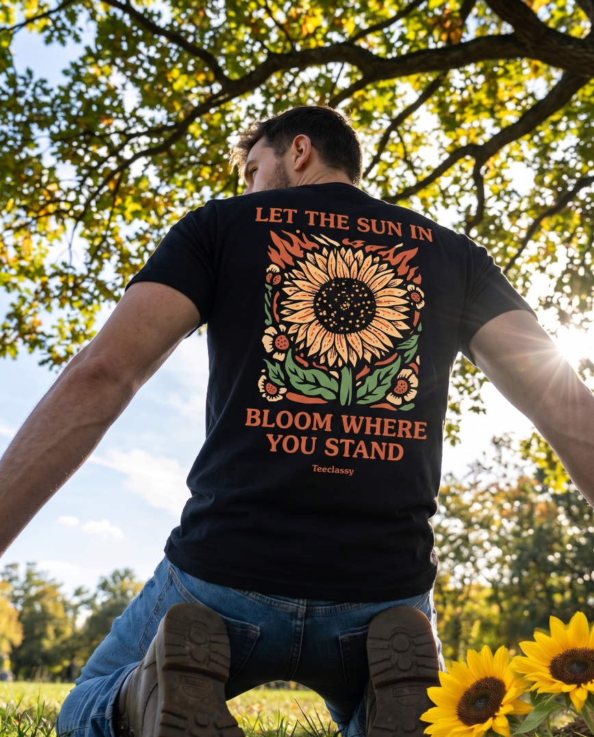 Person wearing a black t-shirt with a sunflower design and text in an outdoor setting